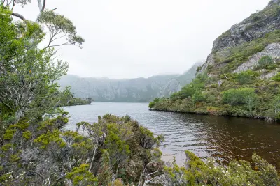 Glacial lake surrounded by rugged mountain slopes and alpine vegetation near Cradle Mountain, Tasmania.