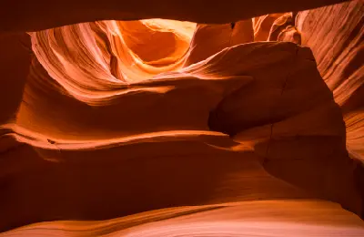 Curved red sandstone walls inside Canyon X near Page Arizona showing layered formations and soft reflected light in a narrow slot canyon.