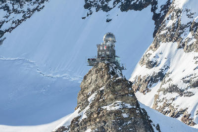 Sphinx Observatory on Jungfraujoch perched on a rocky ridge above snow-covered glacier terrain, Bernese Alps, Switzerland.