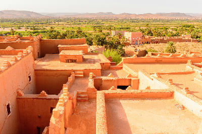 View across the adobe rooftops of Kasbah Taourirt toward the oasis landscape near Ouarzazate, Morocco.