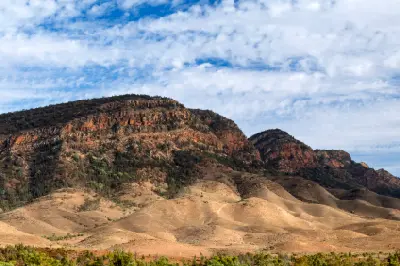 Red sandstone mountain cliffs and dry rolling foothills near Wilpena Pound in the Flinders Ranges, South Australia.