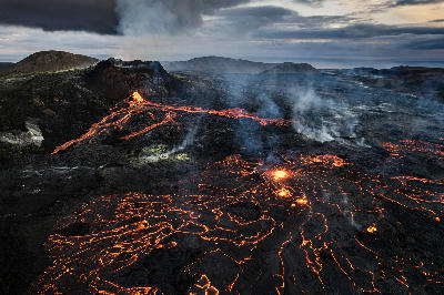 Drone view of glowing lava streams and cooling black crust at Fagradalsfjall volcano, Reykjanes Peninsula, Iceland.