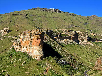 Broad sandstone cliffs and green mountain slopes in Golden Gate Highlands National Park, with layered rock formations overlooking a winding road in the eastern Free State.
