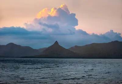 Mount Ida silhouetted beneath glowing clouds across Lake St Clair at dusk, Tasmania, Australia.