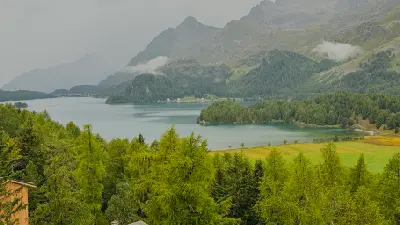 Lake Sils with forested shoreline and low cloud over mountains on an overcast day, Engadin, Switzerland.
