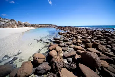 Clear tidal pools, white sand and rounded coastal boulders at Stokes Bay Beach on Kangaroo Island, South Australia.