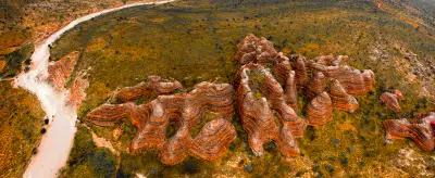 Aerial view reveals the extraordinary striped sandstone formations and narrow valleys of the Bungle Bungle Range surrounded by remote Kimberley wilderness.