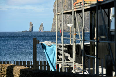 Risin og Kellingin sea stacks offshore from Tjørnuvík with village structures and scaffolding in the foreground, Faroe Islands.