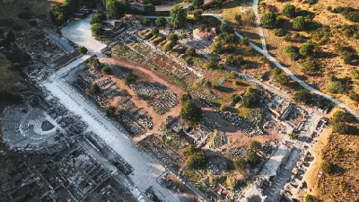 Aerial view across the archaeological ruins of Ephesus in İzmir Province, Turkey, with the ancient theatre, marble streets and remains of buildings visible across the site.