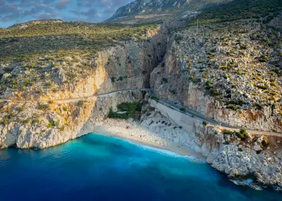Aerial view of Kaputaş Beach, with turquoise Mediterranean water, steep rocky cliffs and the coastal road between Kaş and Kalkan, Turkey.