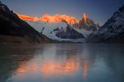 Mount Fitz Roy glowing at sunrise reflected in frozen Laguna Capri in Patagonia, Argentina.