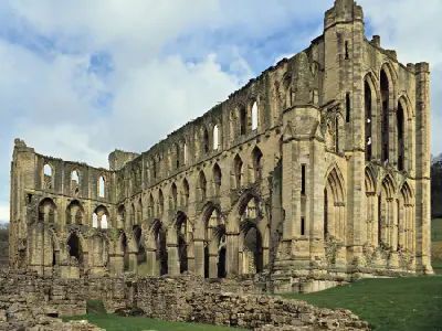 Ground-level view of the towering Gothic arches, stone columns and ruined church walls of Rievaulx Abbey in North Yorkshire.
