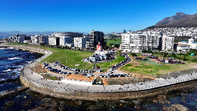 Aerial view of Green Point Lighthouse and the Sea Point Promenade in Cape Town with Table Mountain in the background.