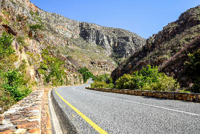 Road curving through Tradouw Pass between steep sandstone cliffs in the Langeberg Mountains near Barrydale, Western Cape, South Africa.