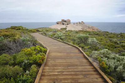Wooden boardwalk leading through coastal shrubs towards Remarkable Rocks on a granite headland overlooking the Southern Ocean in Flinders Chase National Park, Kangaroo Island.