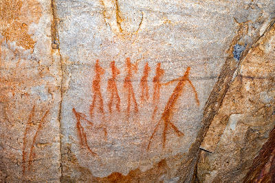 San rock art depicting a group of dancing women painted in red ochre on a sandstone shelter wall at Truitjieskraal in the Cederberg Mountains, Western Cape, South Africa.