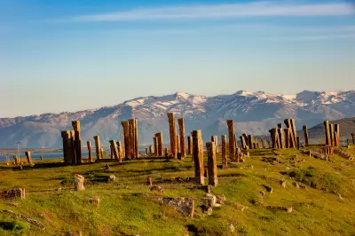 Medieval carved tombstones at Ahlat with green grass and snow-capped mountains in the background near Lake Van, eastern Turkey.