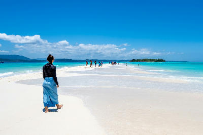 People walking along the Nosy Iranja sandbar in Madagascar with white sand, shallow turquoise water, and tropical islands in the Indian Ocean.