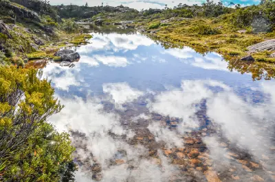 Small alpine tarn reflecting rocky slopes and highland vegetation on the Tarn Shelf in Mount Field National Park, Tasmania.
