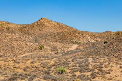 Remote dirt road winding through the arid valleys and rocky hills of Helskloof Pass in the Richtersveld region of South Africa.