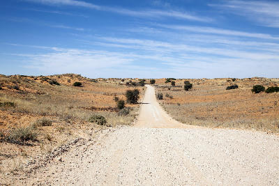 Gravel road crossing red Kalahari dunes in the Kgalagadi Dune System, Northern Cape, South Africa.