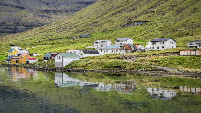 Norðdepil village on Borðoy Island in the Faroe Islands with houses reflected in the fjord.