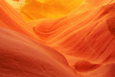 Close-up of Lower Antelope Canyon in Arizona showing flowing sandstone formations with smooth layered curves in warm orange and golden tones.