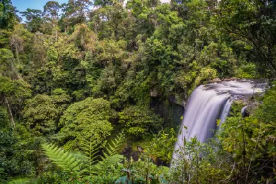 Elevated side view of Zillie Falls cascading over a rocky cliff into a densely forested gorge in Queensland's Atherton Tablelands.