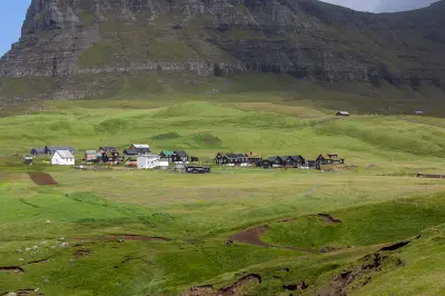 Wide view of Gásadalur village with traditional houses surrounded by grassland and mountains on Vágar Island, Faroe Islands.