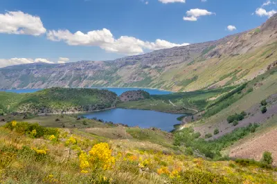 Nemrut Crater Lake and a smaller lake surrounded by green slopes, wildflowers and steep volcanic caldera walls in eastern Turkey.