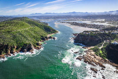 Aerial view of the Knysna Heads and estuary entrance, where steep coastal headlands frame the channel linking the Indian Ocean to the expansive Knysna Lagoon on South Africa's Garden Route.