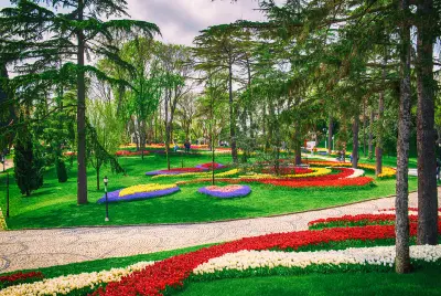 Red, white, yellow and purple tulip beds among mature trees and lawns in Emirgan Park during Istanbul's spring Tulip Festival.