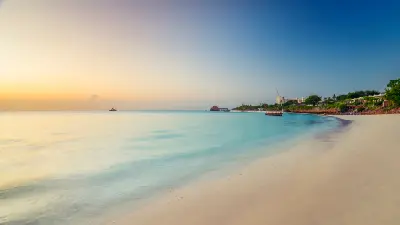 Golden-hour view of Kendwa Beach with white sand, calm turquoise water and the iconic overwater restaurant on Zanzibar's north coast, Tanzania.