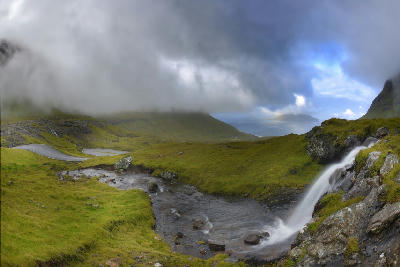 Small waterfall near the curving road overlooking Norðradalur valley toward Koltur island on Streymoy, Faroe Islands.