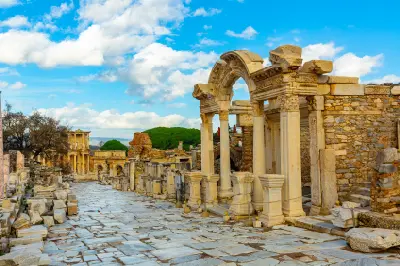 Marble-paved Curetes Street in Ephesus with the ornate Temple of Hadrian on the right and the Library of Celsus visible in the distance.