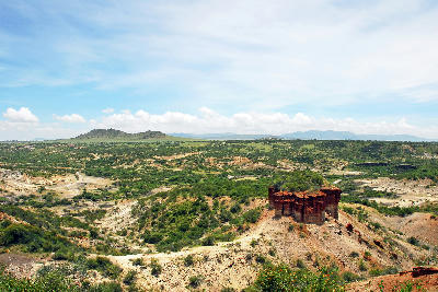 Wide view of Olduvai Gorge showing its eroded valleys, layered sediments and surrounding Serengeti landscape in northern Tanzania, one of the world's most important archaeological sites.