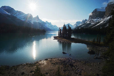 Spirit Island on Maligne Lake with sun flare, reflections, and surrounding snow-capped peaks