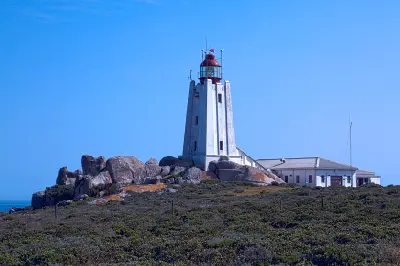 Cape Columbine Lighthouse rising above granite boulders and coastal vegetation within the Cape Columbine Nature Reserve on South Africa’s West Coast.