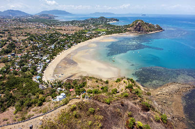 Drone view of Palm Beach on Nosy Be island in Madagascar with turquoise coastal water, sandy bays, reefs, and volcanic tropical coastline.