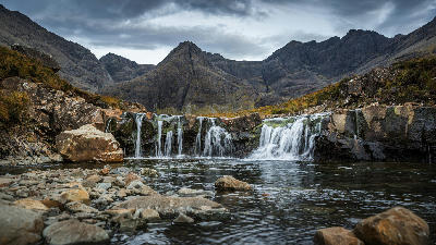 Crystal-clear Fairy Pools waterfalls with the Cuillin mountain range on the Isle of Skye, Scotland.