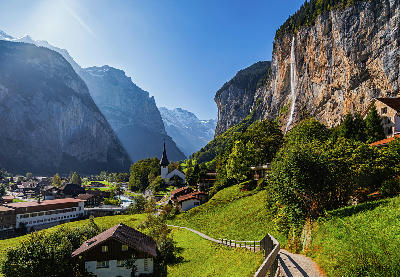 Staubbach Falls flowing down a high cliff above Lauterbrunnen village with alpine valley and mountains in Switzerland