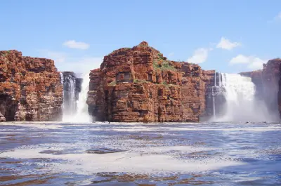 Twin waterfalls plunge over towering red sandstone cliffs into the King George River.