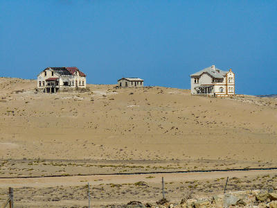 Abandoned colonial buildings partially buried by desert sand in Kolmanskop ghost town, Namibia.