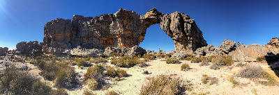 Wolfberg Arch towering above hikers in the Cederberg Wilderness, surrounded by rugged sandstone terrain and mountain vegetation in the Western Cape, South Africa.