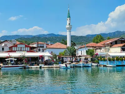 Waterfront village of Üçağız in Kekova Bay, Antalya, Turkey, with small fishing boats, red-roofed houses, restaurants and a mosque minaret reflected in calm Mediterranean water.