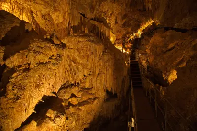 Illuminated limestone formations and visitor stairs inside Mammoth Cave near Margaret River, Western Australia.