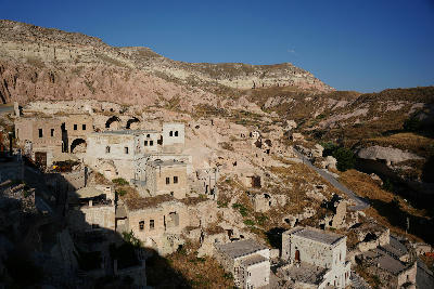 Historic cave dwellings overlooking Rose Valley in Cappadocia, Turkey, with pink volcanic slopes and layered cliffs rising behind Çavuşin Village.