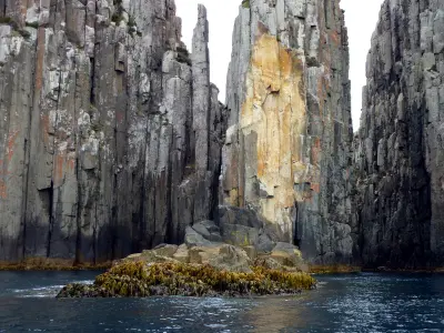 Vertical dolerite sea cliffs and rock columns along the Tasman Peninsula coast in Tasmania.