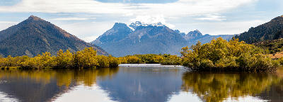 Panoramic view of Glenorchy Lagoon with autumn trees and mountain reflections near Glenorchy, South Island, New Zealand.