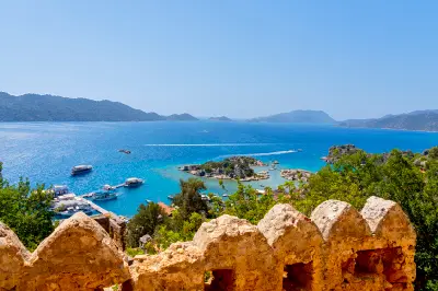 View from Kekova Castle in Kaleköy, Antalya, across vivid blue Mediterranean waters dotted with rocky islands and tour boats.